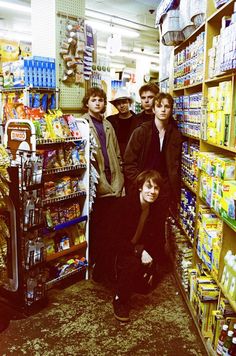 a group of young men standing in front of a store shelf filled with drinks and condiments