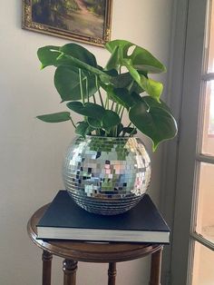 a mirror ball planter sitting on top of a table next to a book and window