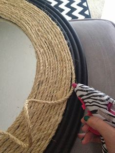 a person is holding a piece of rope next to a round mirror on a couch