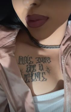 a woman with tattoos on her chest is wearing a pink shirt and has a chain around her neck