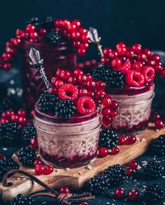 two jars filled with berries sitting on top of a table