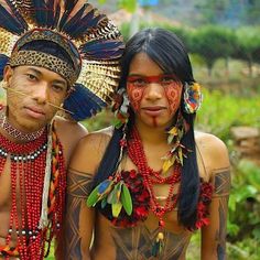 two people dressed in native american clothing posing for the camera