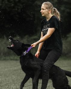 a woman is playing with her dog in the rain