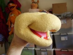 a hand holding up a yellow stuffed animal with its mouth open and teeth wide open