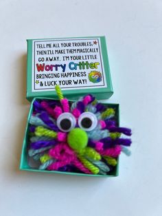 an open green box with a purple and green stuffed animal in it's mouth