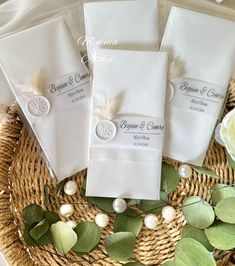 four white folded napkins sitting on top of a wicker basket next to flowers