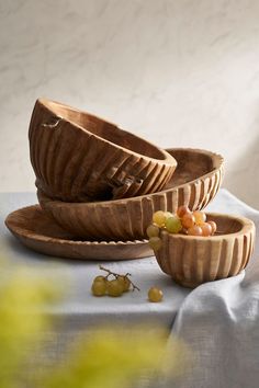 three wooden bowls with grapes in them on a table