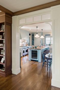 an open kitchen and dining room with hardwood floors, white walls, and wood trimmings