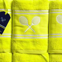 three yellow towels with tennis rackets on them and a tag attached to the towel