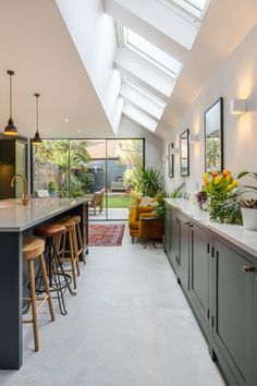 a kitchen with lots of counter space and stools next to an open floor plan