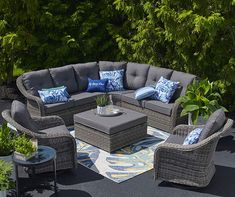 a couch and coffee table on a patio surrounded by greenery