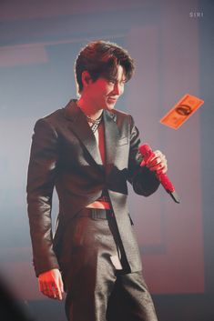 a man in a suit and tie holding a red umbrella while standing next to a microphone