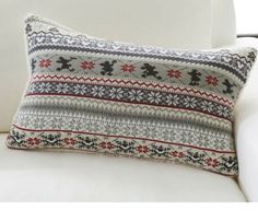 a white couch with a decorative pillow on it's back and an embroidered reindeer design