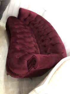 a large red couch sitting on top of a white floor next to a chair and ottoman