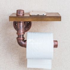 a toilet paper roll is hanging on the wall next to a wooden shelf with a cell phone