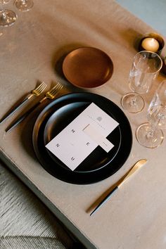 a place setting with black plates and silverware