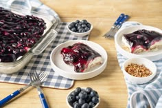 blueberry cheesecake in a glass dish on a table with other desserts and utensils