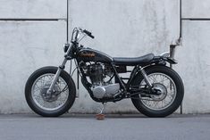 a black motorcycle parked next to a white wall