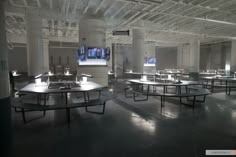 an empty room with tables and televisions on the wall