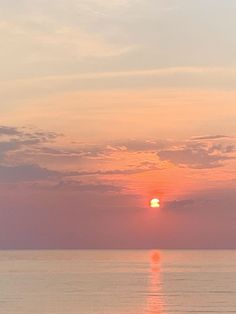 the sun is setting over the ocean with boats in the water