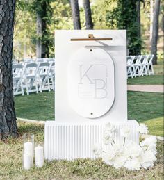 an outdoor ceremony setup with white flowers and candles on the grass, surrounded by trees