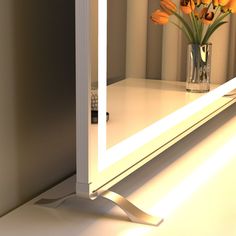 a vase filled with orange flowers sitting on top of a white shelf next to a mirror