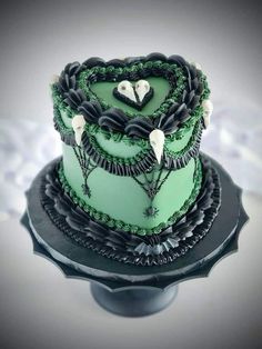 a three tiered cake with green frosting and black icing on the top