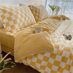 a yellow and white checkered comforter on a bed with two pillows, one has a pillow case