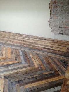 an empty room with wooden flooring and exposed brick wall in the background, showing only one piece of wood left on the floor