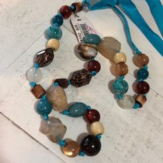 Beautiful Ceramic And Wood Beads On A Blue Ribbon Necklace. You Can Easily Untie The Ribbon And Adjust The Length To Suit You. Brown Polished Beads For Beach, Adjustable Brown Beaded Necklace With Gemstone Beads, Brown Gemstone Beads Necklace For Beach, Cookie Lee Jewelry, Ribbon Necklace, Blue Ribbon, Wood Beads, Blue Brown, Womens Jewelry Necklace