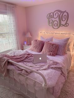 a laptop computer sitting on top of a white bed in a room with pink walls