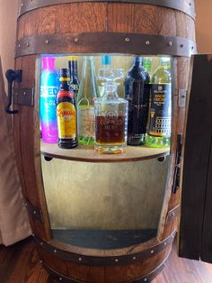 a wooden barrel filled with liquor bottles on top of a table next to a mirror