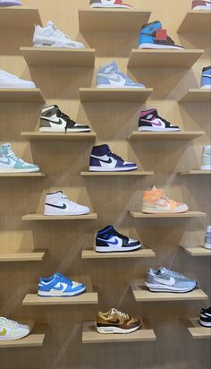 a display case filled with lots of different types of shoes on wooden shelvings