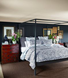 a four poster bed in a bedroom with blue walls and carpeted flooring on the other side