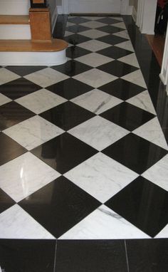 a black and white checkered floor in a house with stairs leading up to the front door