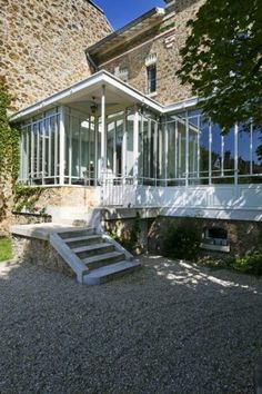 the house is surrounded by stone and glass walls, with stairs leading up to it