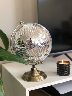 a mirror ball sitting on top of a white table next to a vase with a candle