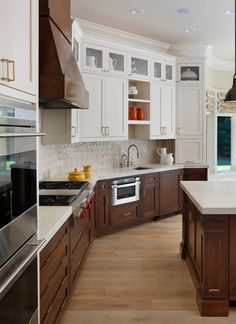 a large kitchen with white cabinets and wood flooring on the countertops, along with an island