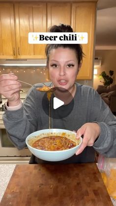 a woman holding a bowl of food in front of her face with the caption beer chili