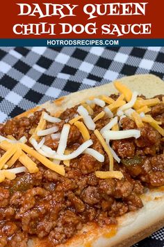 a chili dog with cheese on top is sitting on a black and white checkered table cloth