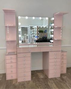 a pink vanity with lighted drawers and mirror