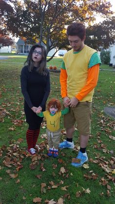 a man and woman standing next to each other in the grass with leaves on the ground