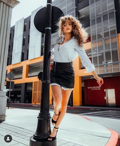 a woman standing on top of a pole next to a street light