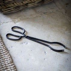 a pair of black scissors sitting on top of a table next to a woven basket