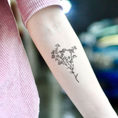 a woman's arm with a small flower tattoo on the left side of her arm