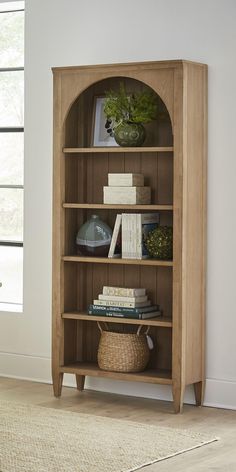 a wooden bookcase with books and plants on top of it in a living room