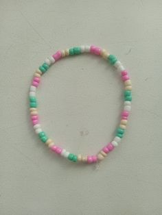 a bracelet with multicolored beads is displayed on a white surface in front of a wall