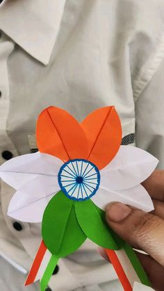 a person holding up a paper flower with the india wheel on it's center