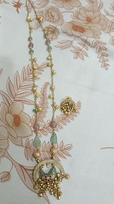 a close up of a necklace on a table cloth with flowers and leaves in the background