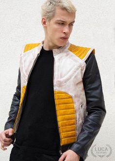 a man with blonde hair wearing a yellow and black star wars jacket, standing in front of a white wall